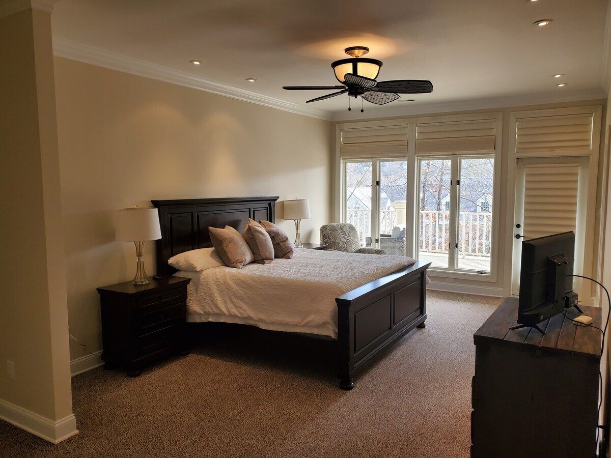 A bedroom with a bed, bedside tables, a ceiling fan, and a television.