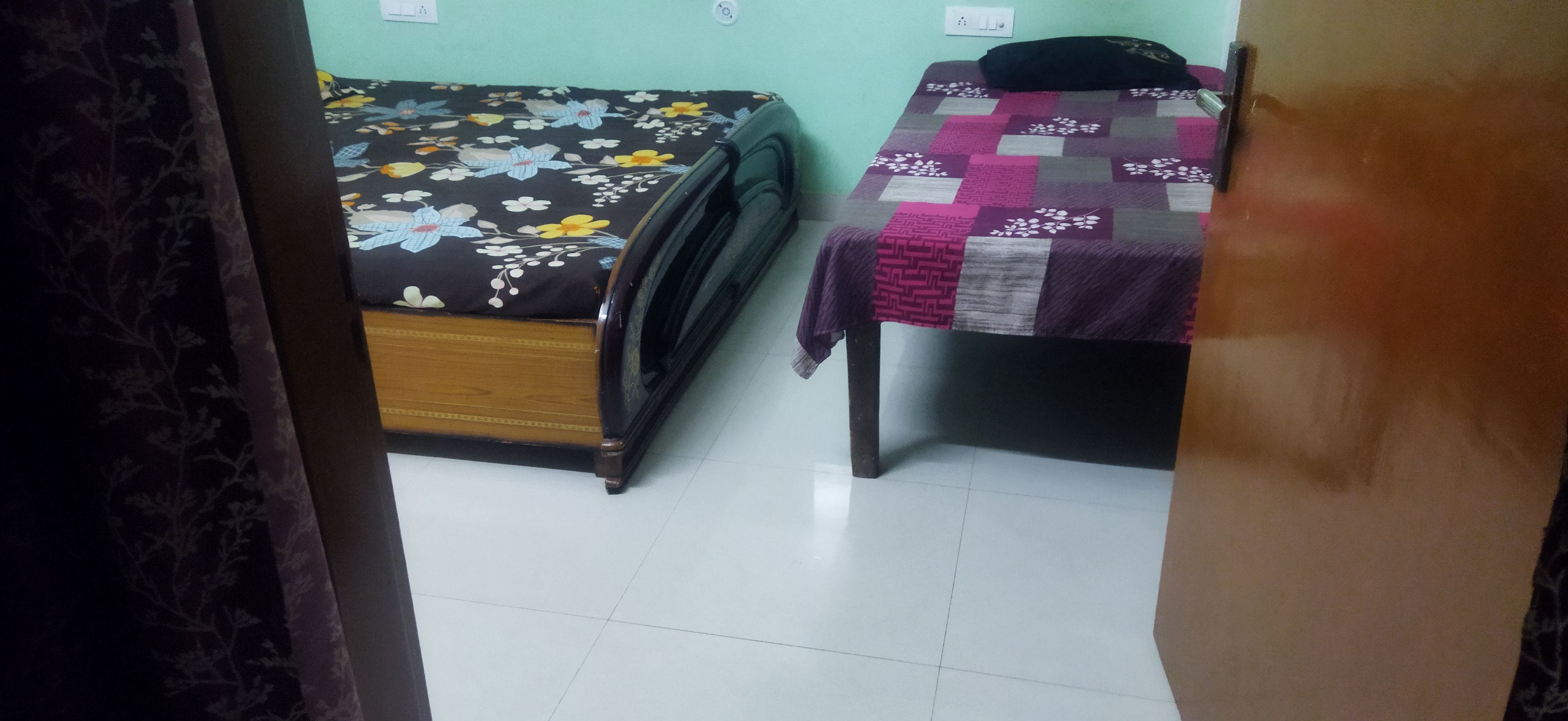 A room with a bed and a table, both with patterned bedspreads.