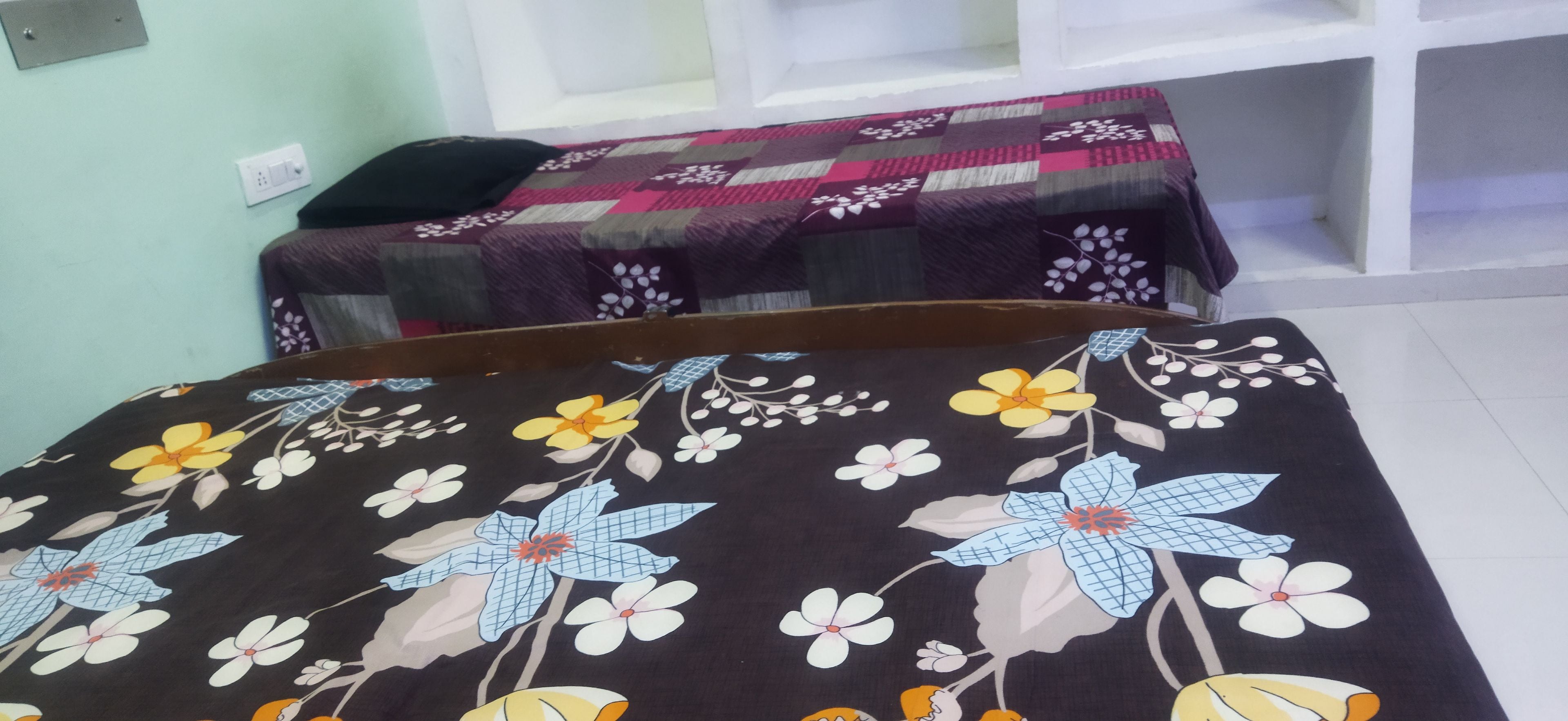 Una habitació amb dos llits, cadascun cobert amb un edredó de motius florals.