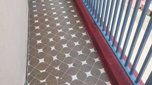 A balcony with a patterned floor, a blue railing, and a view of neighboring buildings. - Arya Sadan Homestay (Mathura)