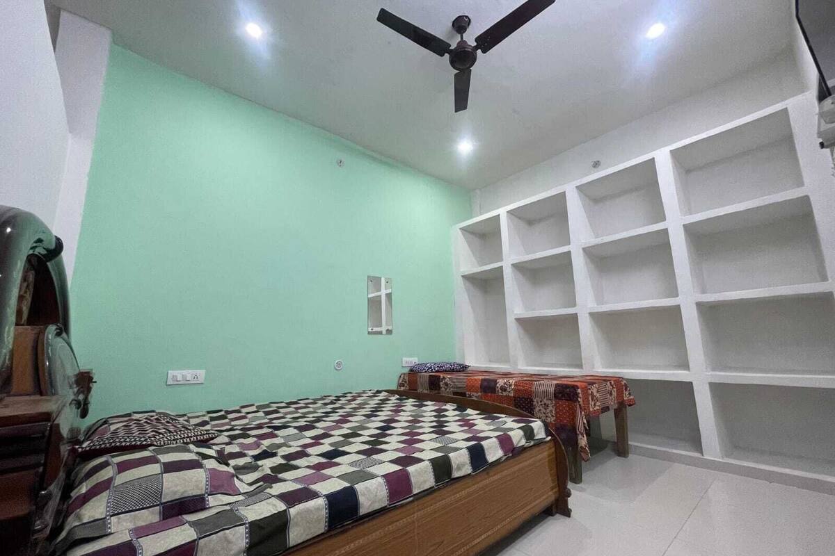 Un dormitorio con cama de madera, ventilador de techo y estanterías empotradas.