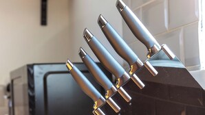 A kitchen counter with a black knife block holding several knives. - 3 Bed Home - Sleeps 8 - Stoke City fc - Parking (Stoke-on-Trent)