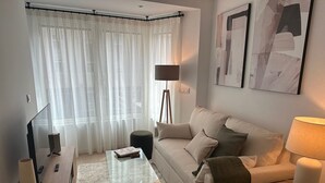 A modern living room with a sofa, coffee table, and a lamp. - Apartamentos Turísticos en Albacete (Albacete)
