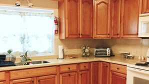 A kitchen with wooden cabinets, a sink, a toaster, and a stove. - Charming Central 1-Bedroom Apartment Close To City Of Hamilton (Devonshire Parish)