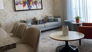 A modern living room with a sofa, two armchairs, a coffee table, and a painting on the wall. - Breakfast Included Regatta Living II 404 (Santo Domingo)