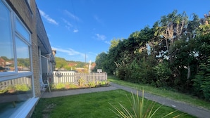 A residential backyard with a lawn, a wooden fence, and a potted plant. - Seaside Haven Retreat - 2 Bedroom Apartment (Skegness)