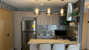 A modern kitchen with a granite countertop, stainless steel appliances, and a bar area with stools. - RL2 504 in Santo Domingo de Guzm n (Santo Domingo)