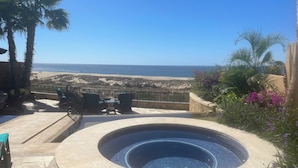 A hot tub with a stone surround, outdoor seating, and a view of the beach. - Novaispania Estates Governor (Cabo San Lucas)