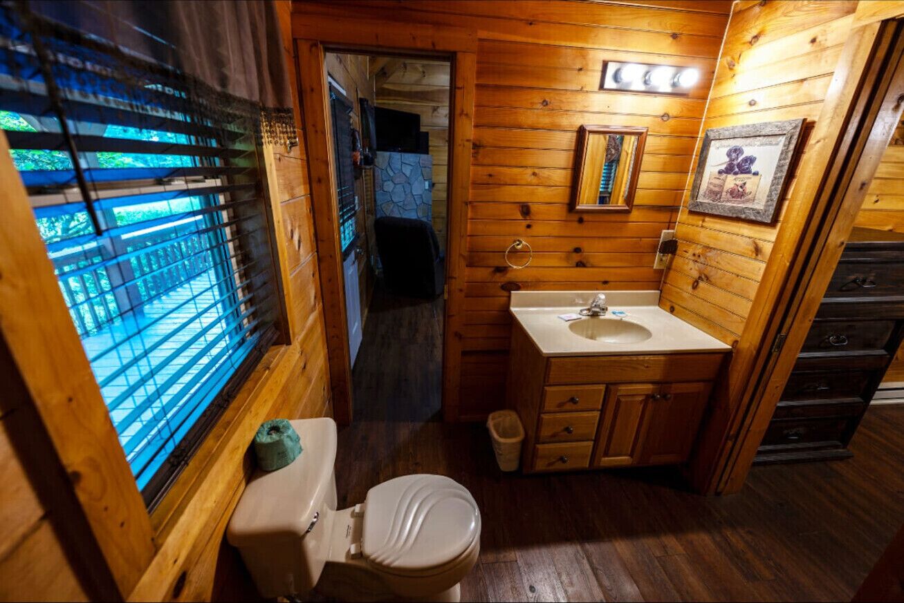 Ein Badezimmer mit Holzeinrichtung, Toilette, Waschbecken und Spiegel.