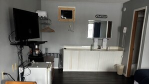 Ein kompakter Wohnbereich mit Essbereich, Küchenzeile und kleinem Badezimmer.