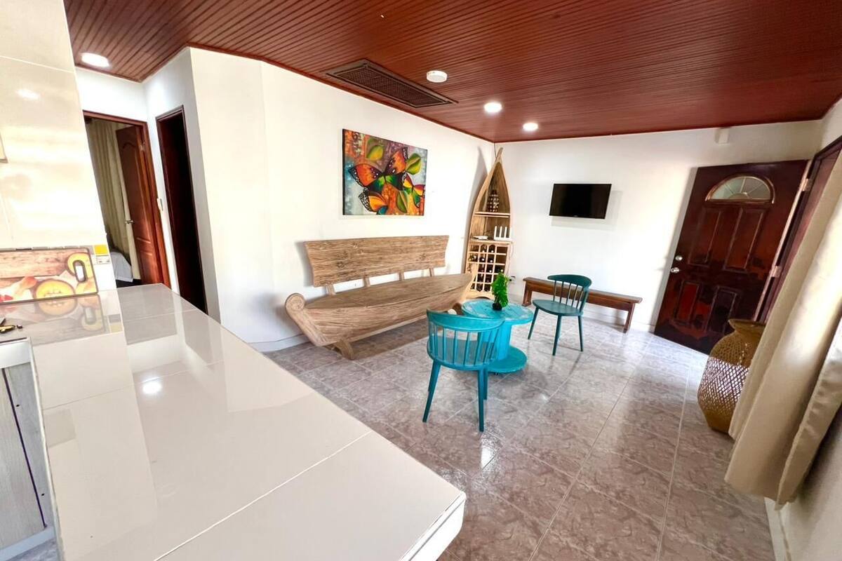 Un interior moderno con una mesa blanca, un banco de madera y una obra de arte colorida en la pared.