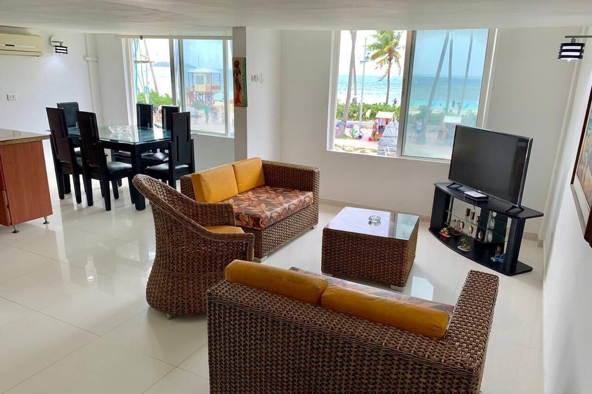 Amplia sala de estar con muebles de mimbre, una mesa de comedor y un televisor.