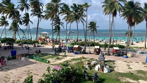 Ein Strand mit Palmen, einem Rettungsturm und entspannten Menschen.