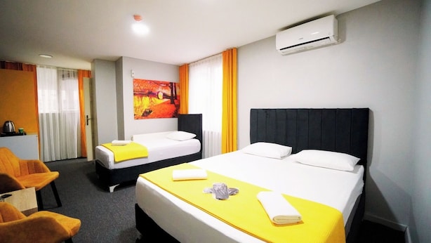 A hotel room with two beds, a desk, and an air conditioning unit. - Polo Suit Otel (Istanbul)