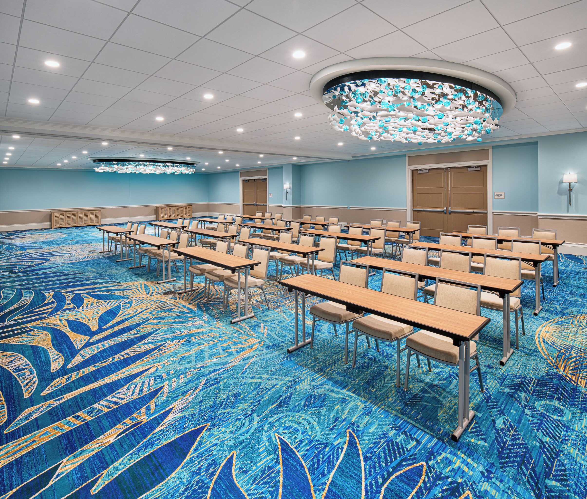 A conference room with a blue carpet, multiple tables, and chairs arranged for meetings.