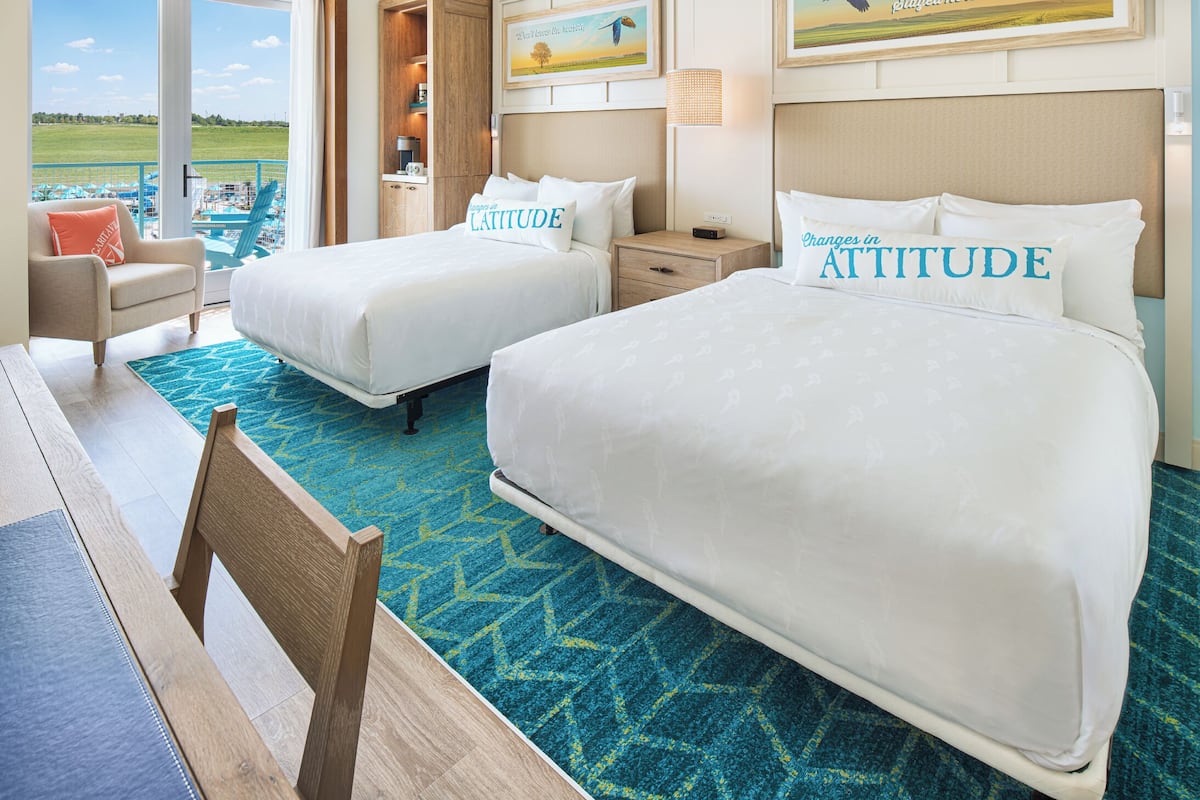 Habitación de hotel con dos camas, vista al mar y un cuadro en la pared.