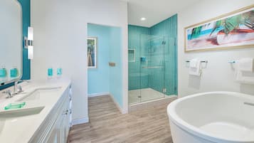 Un baño moderno con dos lavamanos, una bañera grande y una ducha con paredes de cristal.
