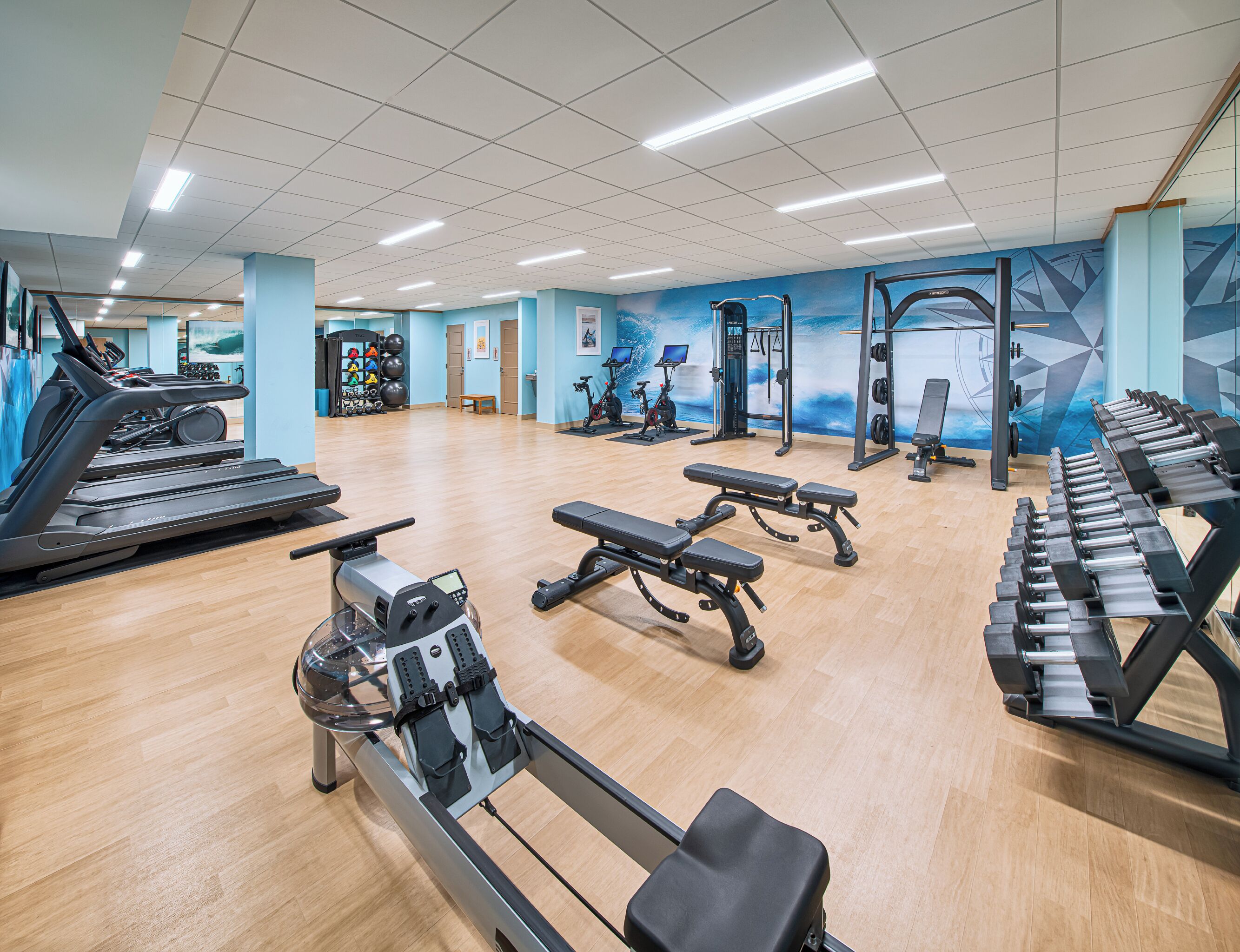 A spacious gym with treadmills, rowing machines, and weight benches.