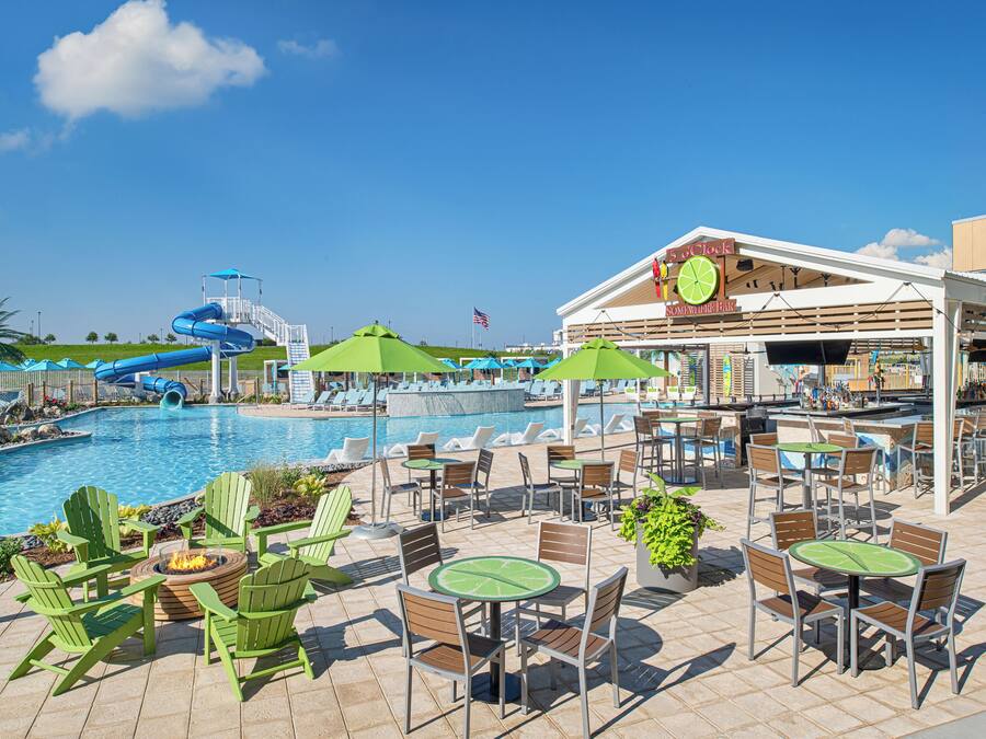 Un espace aménagé au bord de la piscine, avec des chaises longues, des tables et un bar.