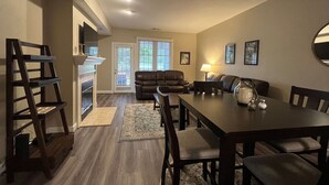 Un salon avec une cheminée, un coin repas avec une table et des chaises, et un canapé.