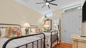 A bedroom with two beds, a ceiling fan, a wooden dresser, and a door leading to another room. - Downtown Village of Pinehurst 2BR/2BA (Pinehurst)
