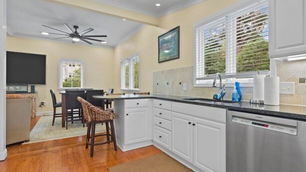 A modern kitchen with white cabinetry, a Bosch dishwasher, and a dining area with wicker chairs. - Downtown Village of Pinehurst 2BR/2BA (Pinehurst)