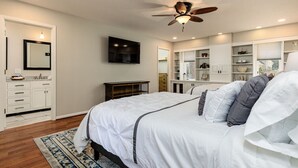 Ein Schlafzimmer mit Bett, Deckenventilator, Einbauschränken und einem großen Fenster.
