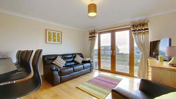 A living room with a leather sofa, a wooden coffee table, and a TV on a wooden cabinet.