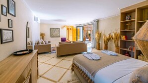 A modern bedroom with a large bed, a sofa, and a desk. There are framed pictures on the wall and a bookshelf. - To complete (Marrakech-Safi)