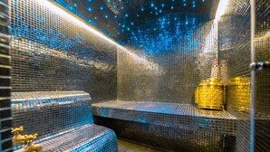A sauna with mosaic tile walls and benches, a golden statue, and a tiled floor. - To complete (Marrakech-Safi)
