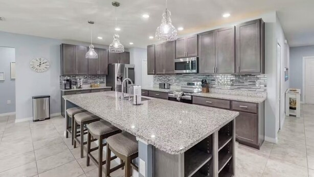 A modern kitchen with granite countertops, stainless steel appliances, and pendant lighting.
