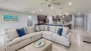 A spacious living room with a sectional sofa, a coffee table, and a ceiling fan.
