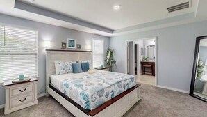 A bedroom with a large bed, bedside tables, a nightstand, and a door leading to a bathroom.
