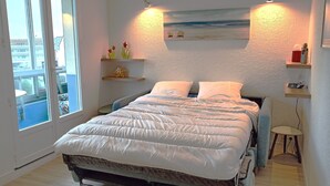 Une chambre à coucher comprenant un lit, une fenêtre et une étagère fixée au mur, ornée d’objets décoratifs.