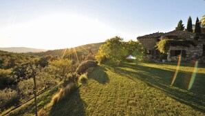 A stone building with a sloped roof, surrounded by a grassy area and trees. - Stunning villa with large pool in the heart of Chianti 12km from Siena (Radda in Chianti)