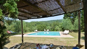 An outdoor pool area with lounge chairs and a table set for a meal, surrounded by trees and a clear sky. - Stunning villa with large pool in the heart of Chianti 12km from Siena (Radda in Chianti)