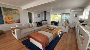 A modern living room with a sectional sofa, a coffee table, and a kitchen area with a white countertop and a bowl.