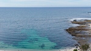 A coastal view with clear turquoise waters, rocky shorelines, and a sandy beach. - Everlong Mollymook - Spacious Home on Beachside Golf Course with Ocean views (Mollymook)