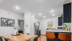 A modern kitchen with a central island, stainless steel appliances, and a dining area with a wooden table and chairs.