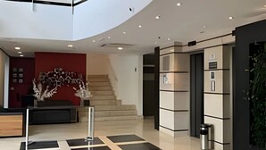 Ένας σύγχρονος χώρος υποδοχής με καμπυλωτή οροφή, μια σκάλα και έναν πάγκο εξυπηρέτησης.