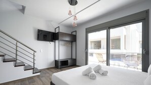 Un dormitorio moderno con una cama grande, un armario empotrado, un televisor en la pared y un balcón con mobiliario exterior.