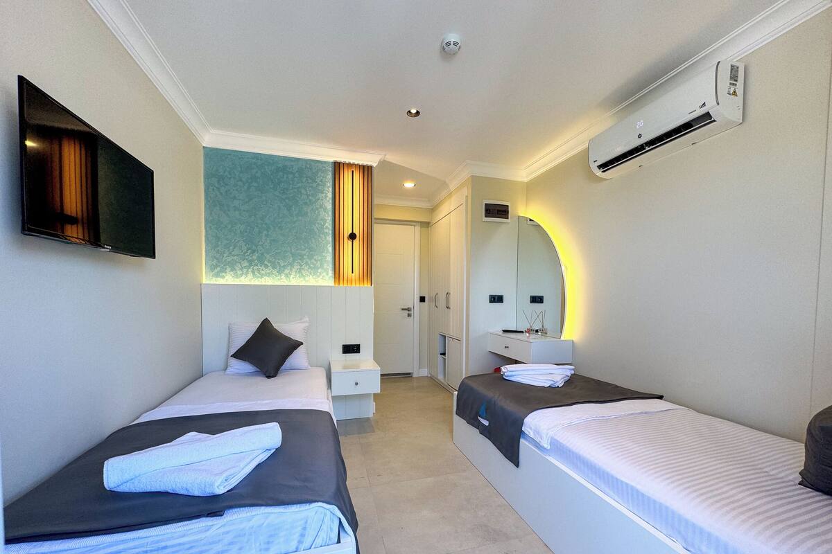 Een hotelkamer met twee bedden, een televisie, een kast en een airconditioner.