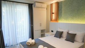 A hotel room with a bed, a nightstand, a wardrobe, and a large window with curtains. - AKPINAR MARIN OTEL (Cesme)