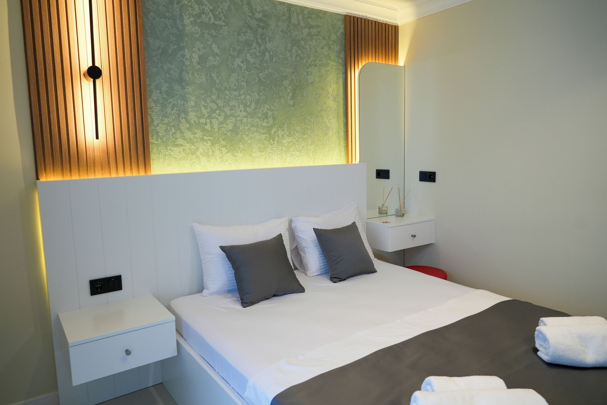 Een moderne hotelkamer met een groot bed, twee nachtkastjes en een spiegel.