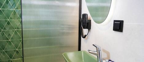 Un baño con un lavabo verde, un espejo y un secador de manos.