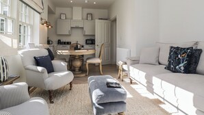 Ein geräumiges Wohnzimmer mit einer Couch, Sesseln, einem Couchtisch und einem Essbereich mit Tisch und Stühlen.