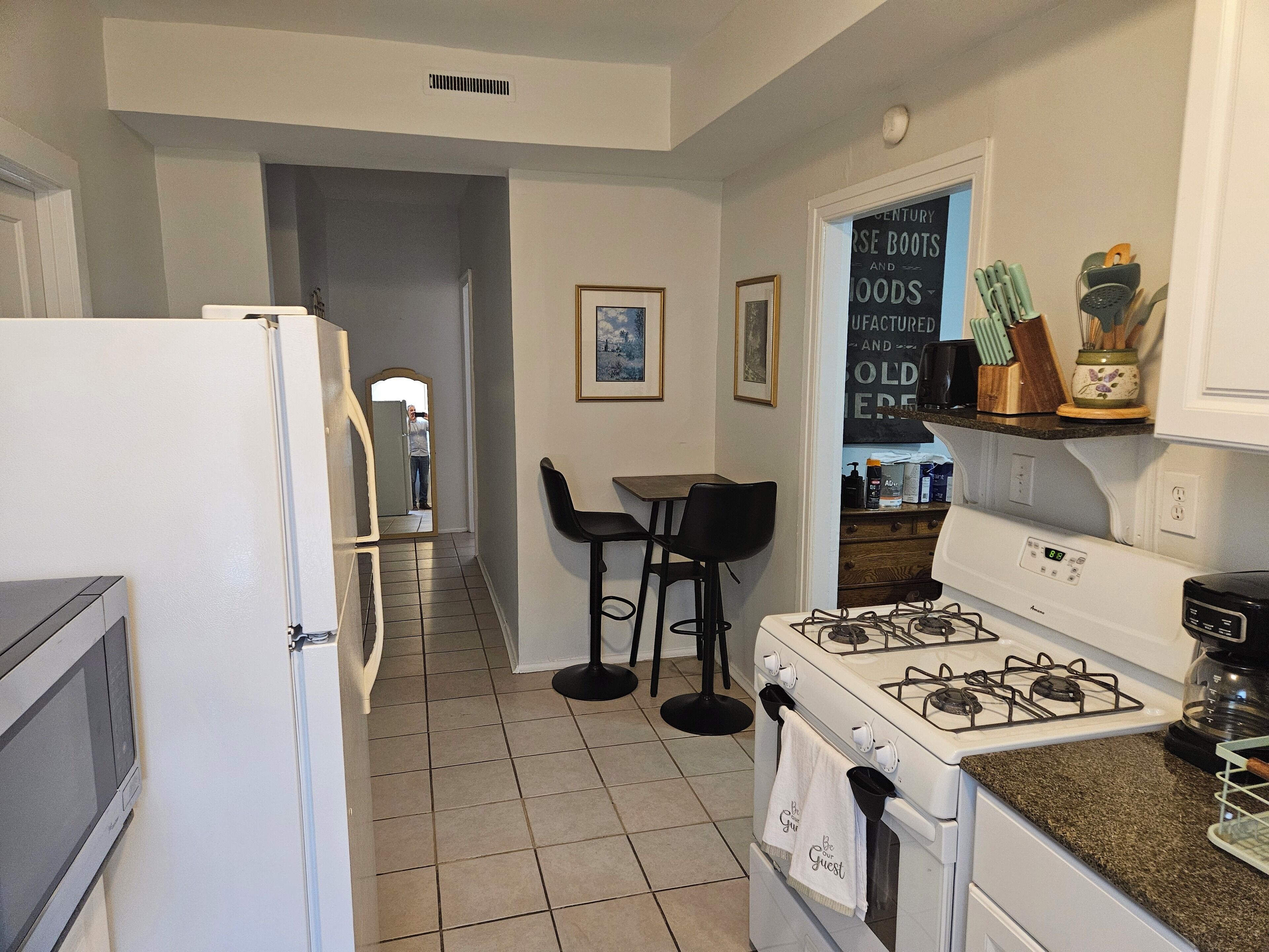 A kitchen with a refrigerator, stove, and bar stools.