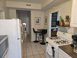 A kitchen with a refrigerator, stove, and bar stools.