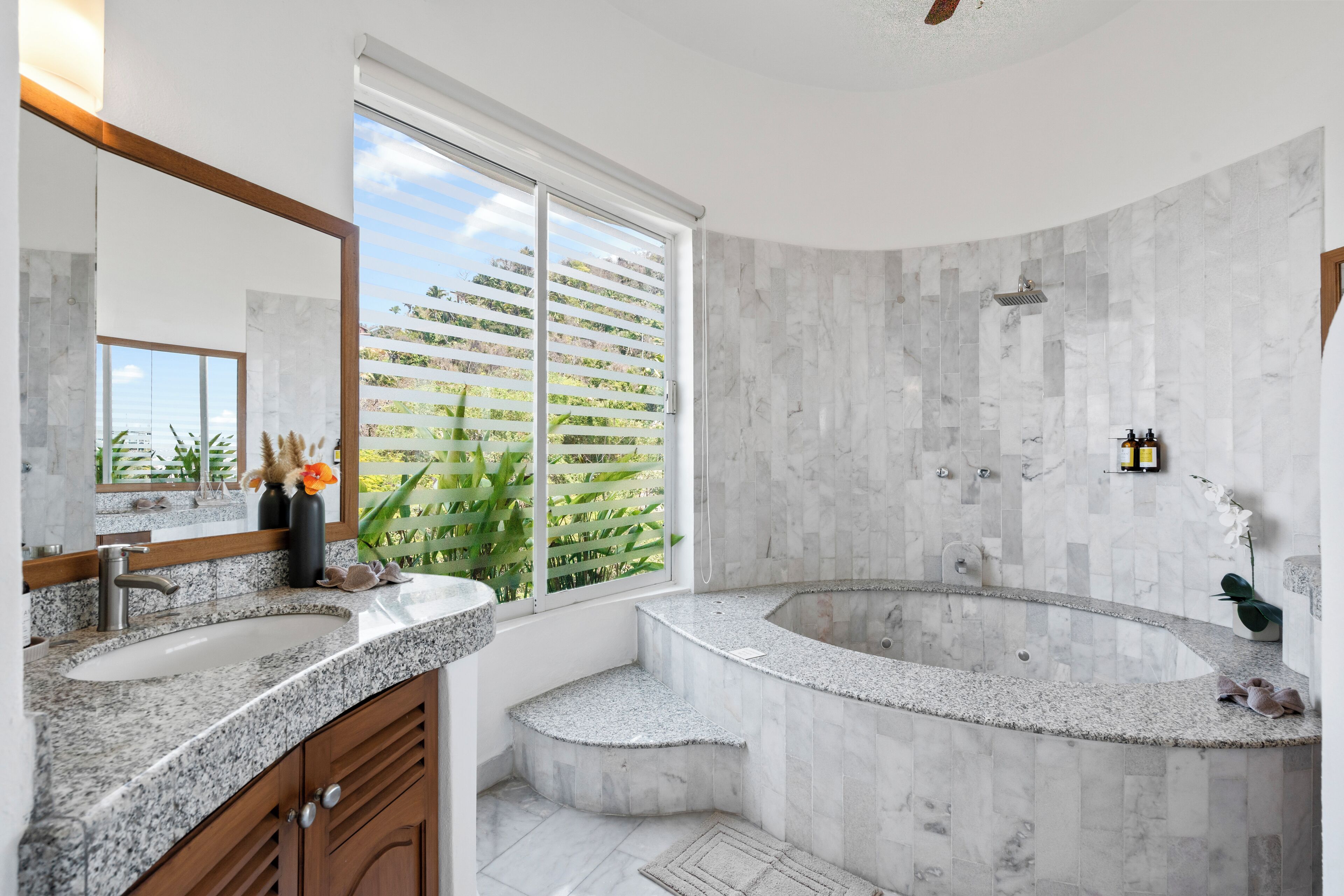 A modern bathroom with a large window, a freestanding bathtub, and a vanity with a sink.