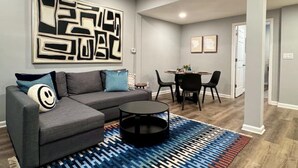 A modern living room with a gray sofa, a coffee table, and a patterned rug.